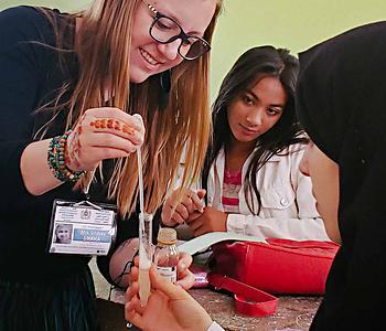 educator using a pipette and test tube with students observing